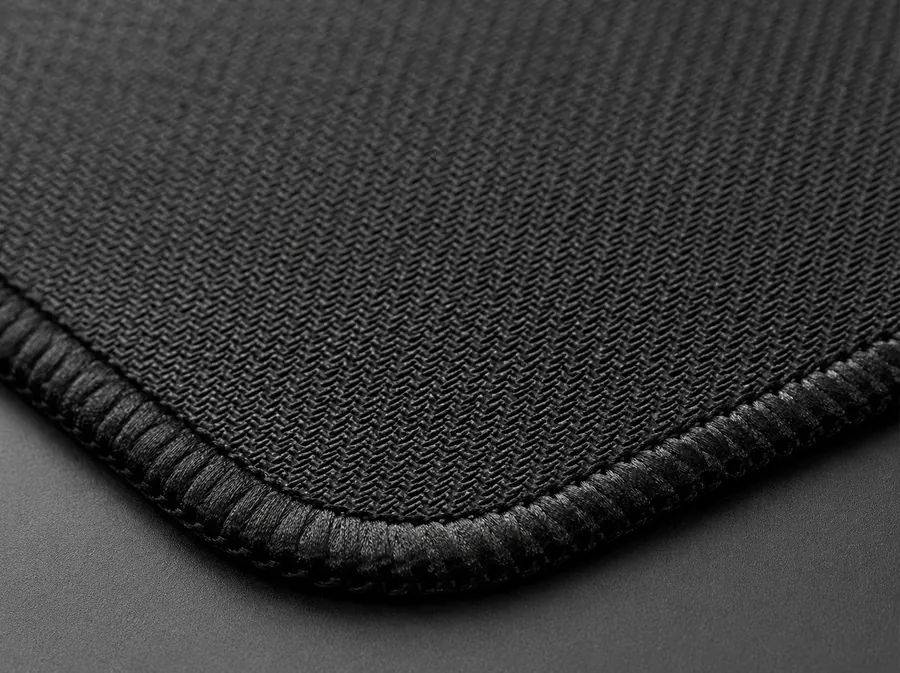 Gros plan du tissage fin et du bord cousu renforcé d'un tapis de souris Tapigami, coin visible en détail